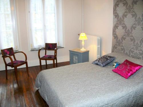 a bedroom with a bed with two chairs and a lamp at Les rosieres 