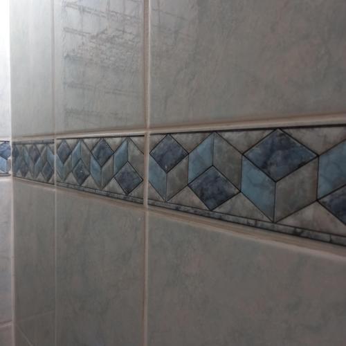 a tiled shower with blue and gray tiles at RIVIJERA LAKES Ada Studio in Belgrade