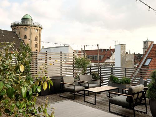 a rooftop patio with tables and chairs and a tower at Apēron Apartment Hotel in Copenhagen