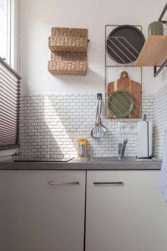 a kitchen with white cabinets and a white tile wall at City Apartment in berühmter Lage in Hildesheim