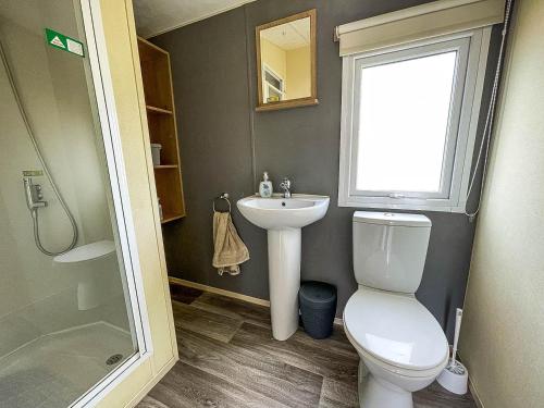 a bathroom with a toilet and a sink and a window at Lovely 8 Berth Caravan At Manor Park Nearby Hunstanton Beach 23107s in Hunstanton