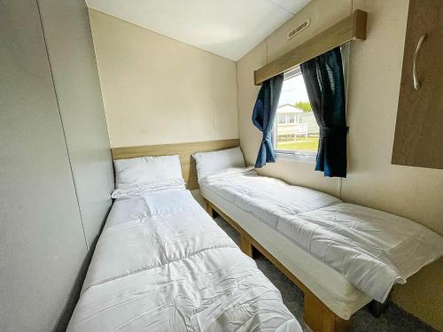 2 camas en una habitación pequeña con ventana en Lovely 8 Berth Caravan At Manor Park Nearby Hunstanton Beach 23107s en Hunstanton