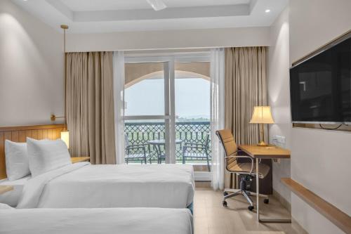a hotel room with a bed and a desk and a window at Fairfield by Marriott Goa Calangute in Calangute