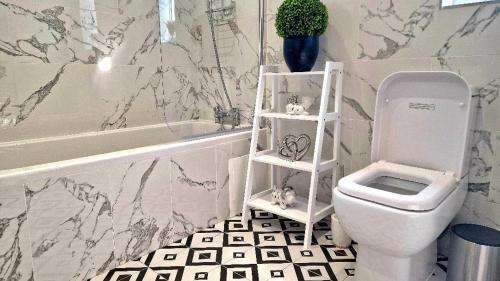 a bathroom with a white toilet and a bath tub at Stunning, clean, free parking home, ideal long stays in West Thurrock