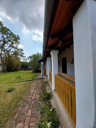 a white house with a wooden fence next to a yard at Körűnéző Vendégház in Nagykörů
