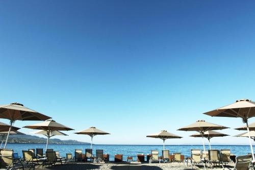 a group of chairs and umbrellas on a beach at Elite City Resort in Kalamata