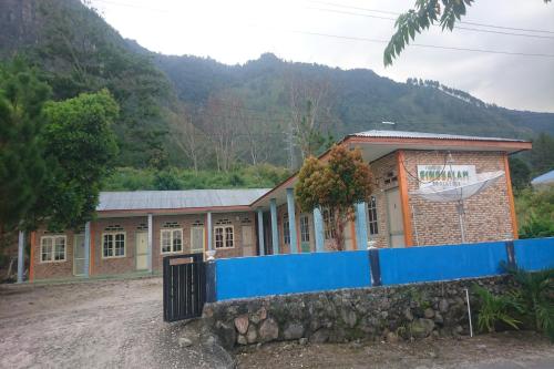 a building with a blue fence in front of it at Penginapan Rindu Alam Soala Gogo in Tongging