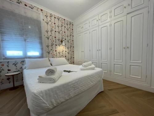 Un dormitorio con una cama blanca con toallas. en VIDAL APARTAMENTOS con parking privado. en Carmona