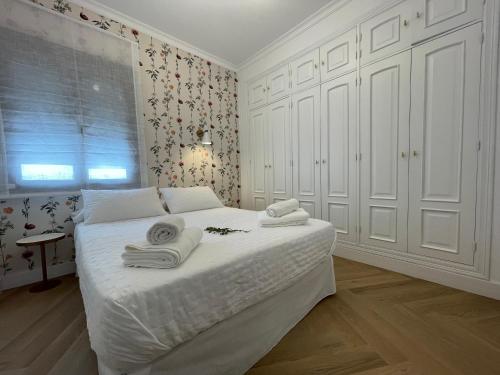 una camera da letto con un letto bianco e asciugamani di VIDAL APARTAMENTOS con parking privado. a Carmona