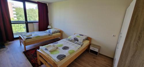 2 Betten in einem kleinen Zimmer mit Fenster in der Unterkunft City Apartment Cologne-Weiden in Köln
