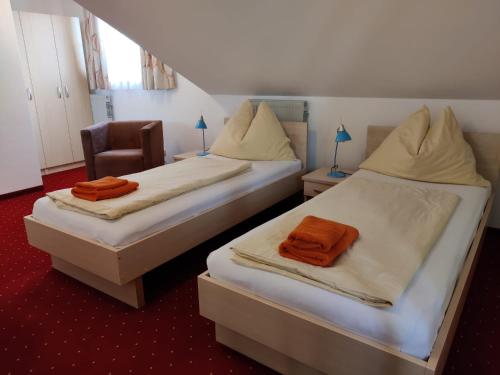 Duas camas com toalhas cor de laranja num quarto em Pension Holzapfel em Sankt Georgen im Attergau