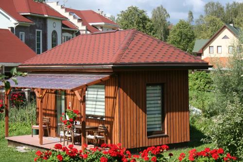 una cabaña con techo en un patio con flores en Beltes Guest House, en Jūrmala
