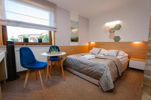 ein Schlafzimmer mit einem Bett, einem Tisch und einem blauen Stuhl in der Unterkunft Hotel Kosmowski in Września