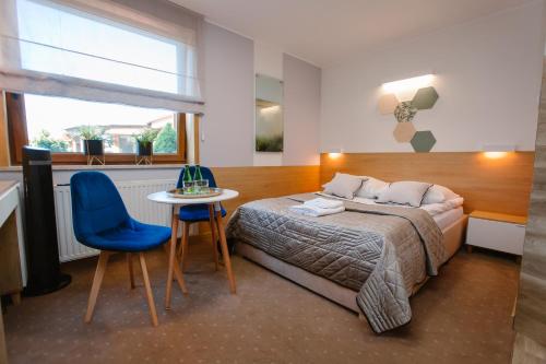 a bedroom with a bed and a table and a blue chair at Hotel Kosmowski in Września