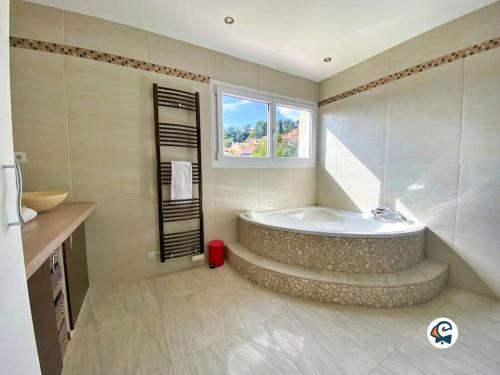 La grande salle de bains est pourvue d'une baignoire et d'une fenêtre. dans l'établissement MAGNIFIQUE VILLA PISCINE PROCHE NICE, à La Trinité