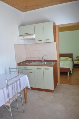 a kitchen with a sink and a table with chairs at Apartments Zora in Vis