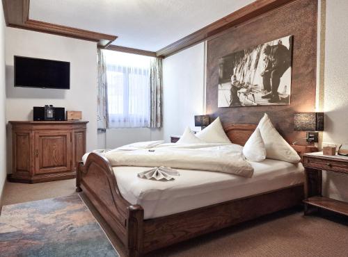 レッヒにあるHotel Jagdhaus Monzabonのベッドルーム1室(大型ベッド1台、木製ヘッドボード付)