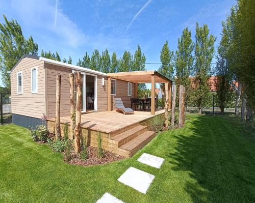 une petite maison avec une terrasse en bois dans une cour dans l'établissement Beachside Vakantiepark, à Blankenberge
