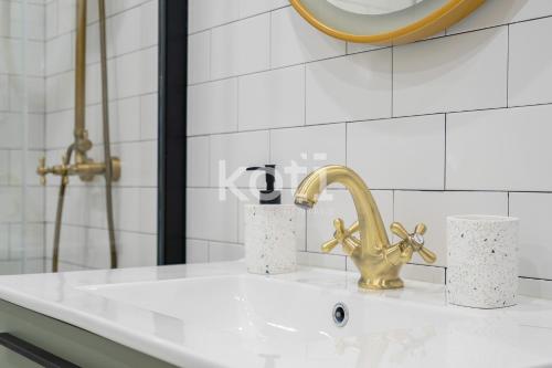 lavabo blanco con grifo de oro en Koti Rentals - Colina Park, en Mijas