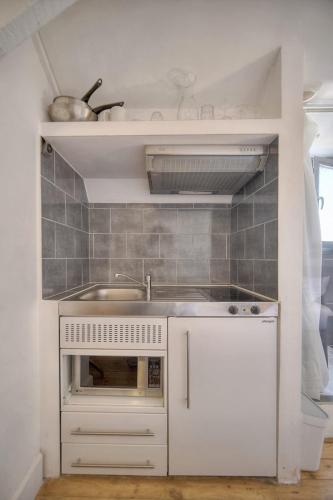 Il comprend une petite cuisine blanche avec un évier et un four micro-ondes. dans l'établissement IMMOGROOM - 2 min from the Palais des Festival and the beaches - ac, à Cannes
