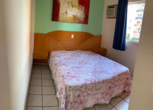a small bedroom with a bed with a pink blanket at Sol das Caldas in Caldas Novas