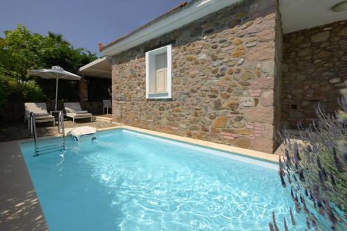 a swimming pool in front of a stone house at Oikies Small Elegant Houses in Mytilini