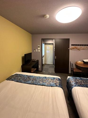 a hotel room with two beds and a desk at Miro Kyoto Nijo Hotel in Kyoto