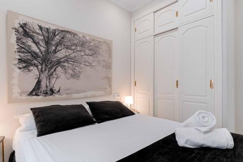 - une chambre dotée d'un lit blanc et d'une peinture sur les arbres dans l'établissement Apartamentos Recaredo 7, Áticos con terraza, à Séville