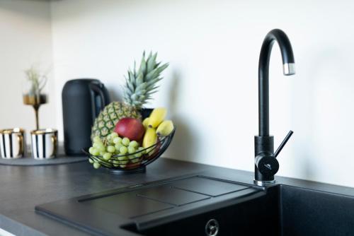 a bowl of fruit on a kitchen counter with a sink at Lazy House Klaipeda in Klaipėda