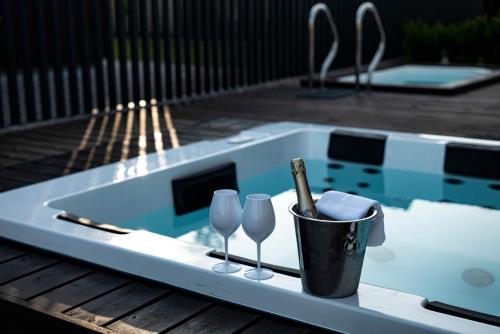 a tray with wine glasses and a bottle on a table next to a pool at Lazy House Klaipeda in Klaipėda