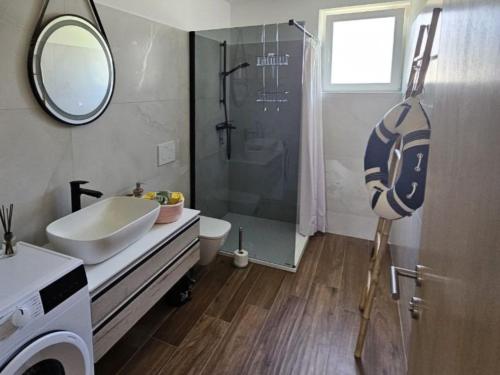 uma casa de banho com um chuveiro, um lavatório e um espelho. em Holiday Apartment Deluxe em Savudrija