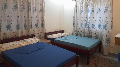 two twin beds in a room with curtains at Crown Apartments in Malindi