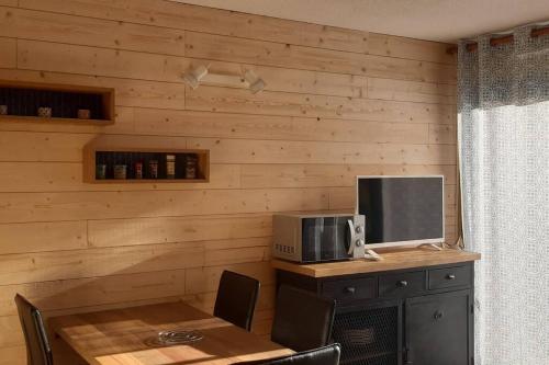 Cette chambre est dotée d'un mur en bois, d'une table et d'une télévision. dans l'établissement REZ DE JARDIN CALME ST LARY PROCHE TELECABINE, à Saint-Lary-Soulan