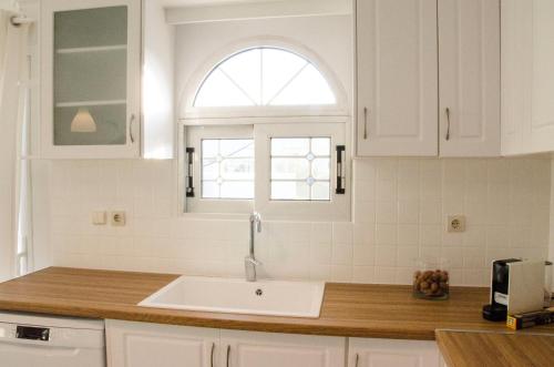 a white kitchen with a sink and a window at Eva's house in Kánithos