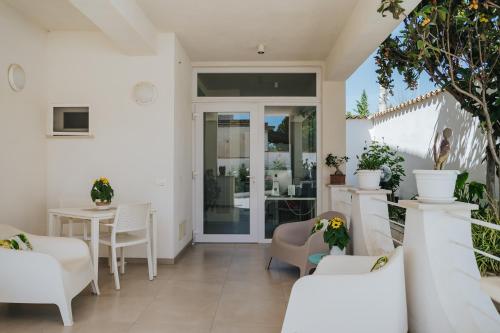 un patio con mobili bianchi, tavolo e sedie di Villa Sece - Luxury Rooms a Agrigento