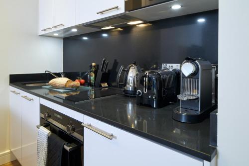 a kitchen with a black counter top with a appliance at Cheval Harrington Court at South Kensington in London