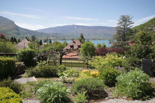 un jardin avec une maison et des montagnes en arrière-plan dans l'établissement Maison de famille à quelques pas du Lac, à Talloires