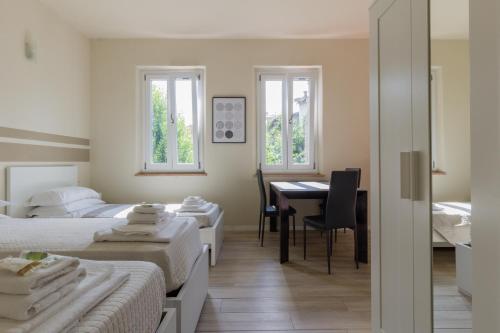 a bedroom with two beds and a desk and a table at Center Rooms in Piacenza