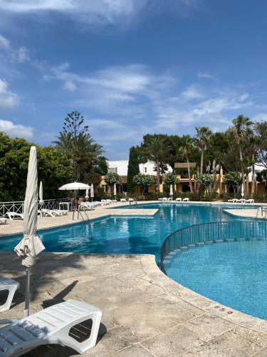 a large swimming pool with chairs and an umbrella at Bungalow Tropical nº6 - Son Xoriguer in Son Xoriguer