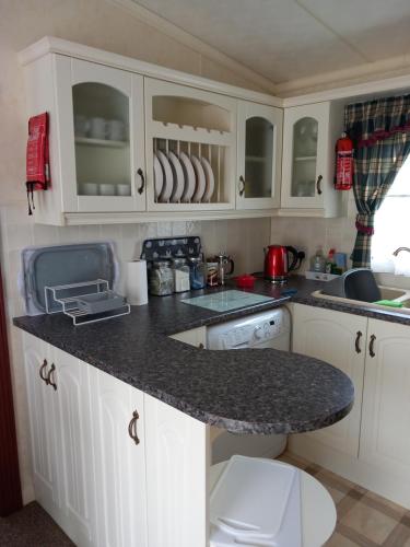 a kitchen with white cabinets and a granite counter top at Cosy comfort in Ingoldmells