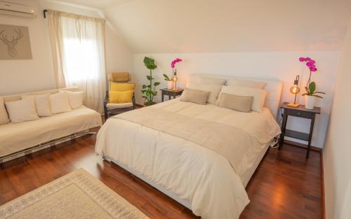 a bedroom with a large white bed and two chairs at Vineyard cottage Jelenov hrib in Smarjeske Toplice