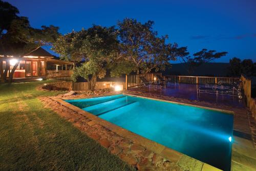 a swimming pool in a backyard at night at Ekuthuleni Lodge in Welgevonden Game Reserve