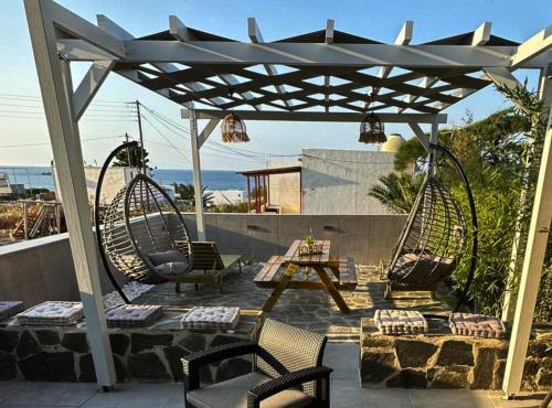 a patio with two swings and a table and chairs at Mora Houses in Mandrakia