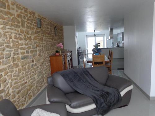 ein Wohnzimmer mit Sofa und Ziegelwand in der Unterkunft Petites fleurs des champs in Puilly-et-Charbeaux