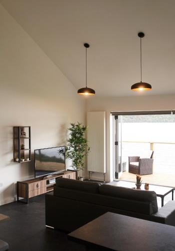a living room with a couch and a tv at Shoreland Lodges - Holly Lodge in Fort Augustus