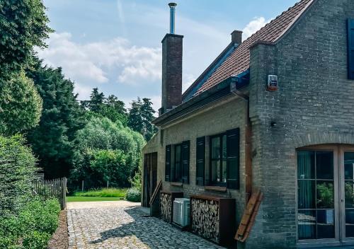a brick building with a door and a yard at Luxe vakantiewoning, Maison Masko, tussen Brugge en Oostende in Jabbeke