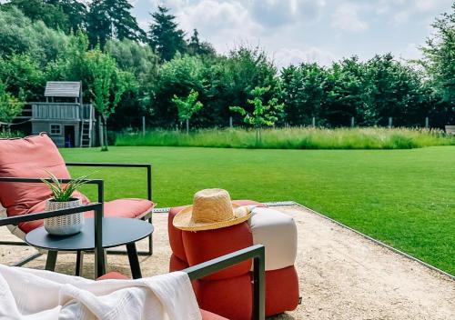 a group of chairs sitting on a patio with a field at Luxe vakantiewoning, Maison Masko, tussen Brugge en Oostende in Jabbeke