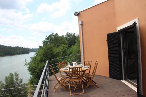 a table and chairs on a balcony with a view of a river at Casa do Rio in Treixedo