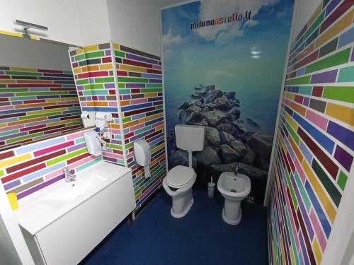 a bathroom with a colorful wall with a toilet and a sink at Milano Ostello in Milan