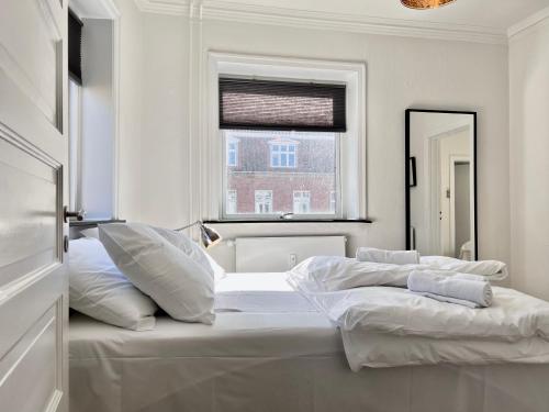 a white bedroom with a large bed and a window at Three Bedroom Apartment In Valby, Valby Langgade 214, in Copenhagen